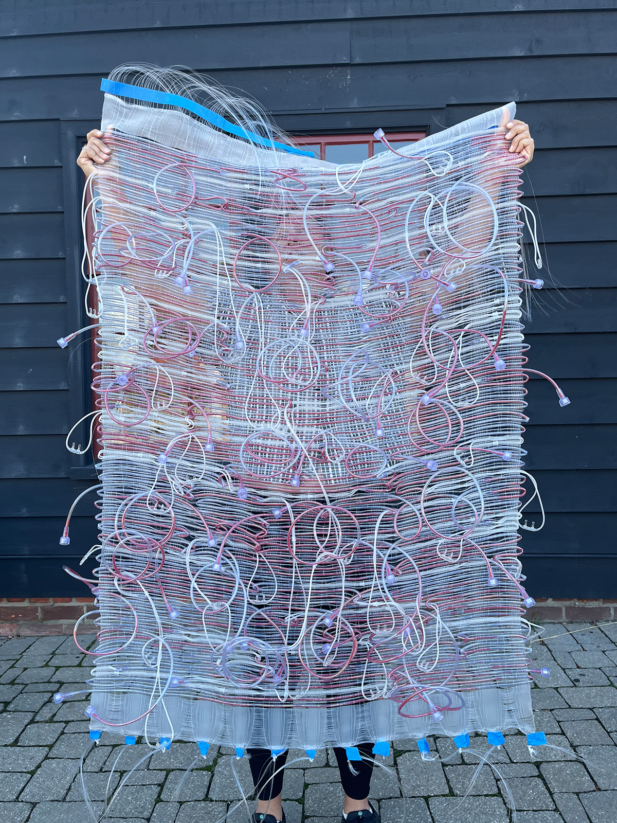 Maggie Thompson holds up a woven piece of artwork