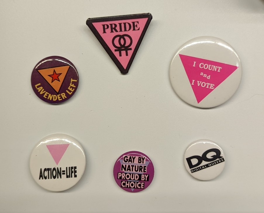 LGBTQ+ Pins/Buttons Six pins/buttons with text related to LGBTQ+ issues, most also featuring triangles